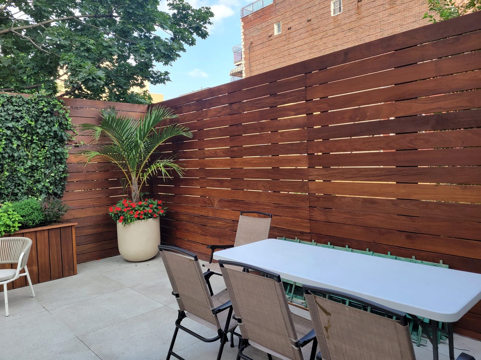 Brooklyn brownstone backyard with horizontal IPE wood fence at twilight