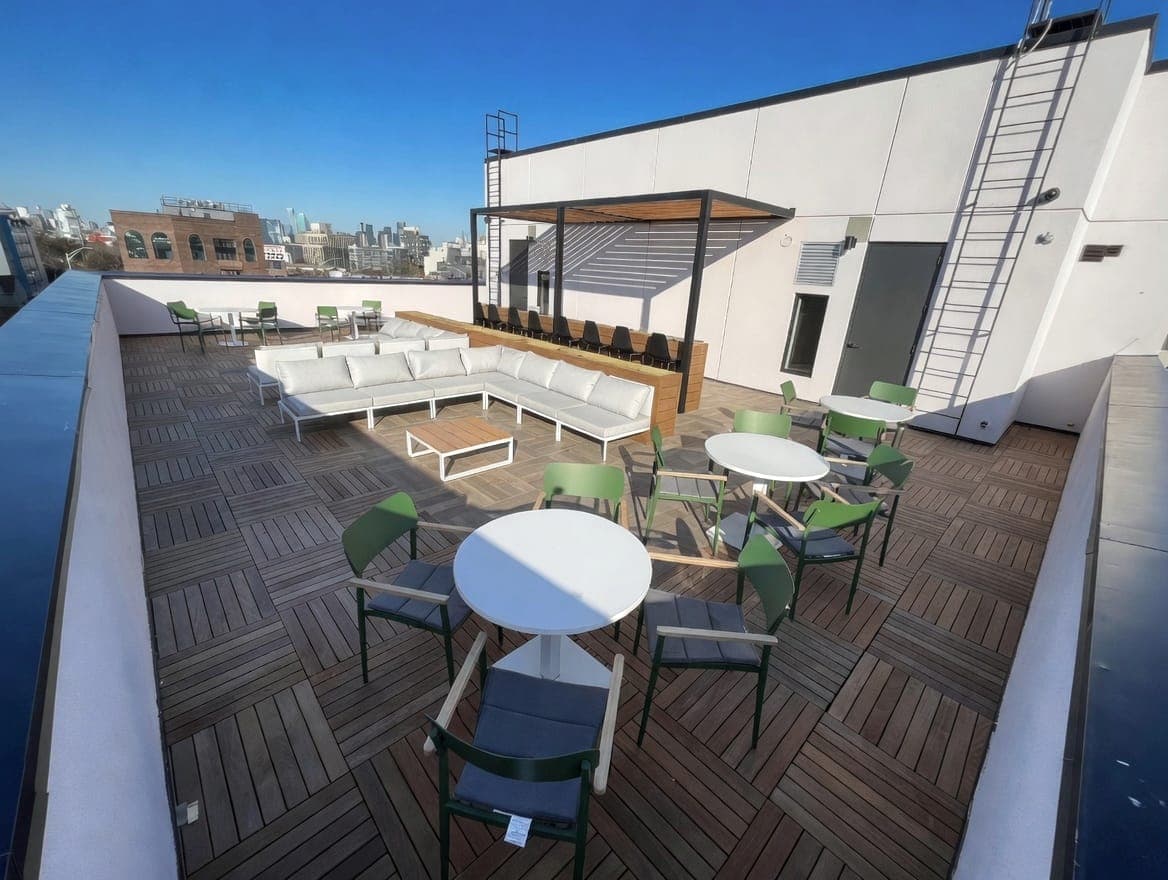 Manhattan rooftop terrace with white sectional seating, pergola, and skyline view